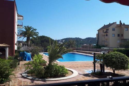Blick auf einen Pool mit Bäumen und Gebäuden in der Unterkunft Fantástico apartamento con piscina en Tossa de Mar in Tossa de Mar
