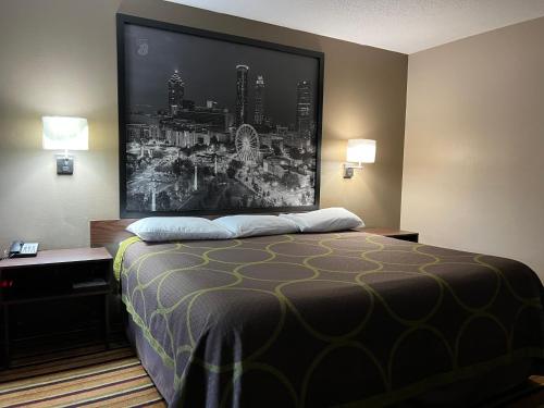 a hotel room with a bed with a large picture on the wall at Super 8 by Wyndham Norcross/I-85 Atlanta in Norcross