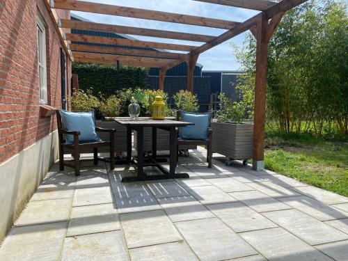 a patio with a table and chairs under a wooden pergola at Heerlijk Gaanderhei in Gaanderen
