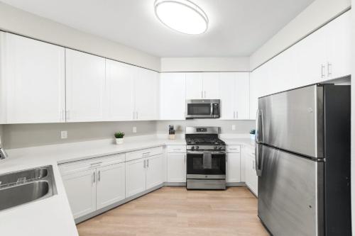 a kitchen with white cabinets and a stainless steel refrigerator at Designer Apt with Jacuzzi, Sky Lounge, Gym Access in Sparks
