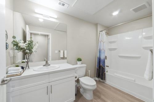 Baño blanco con aseo y lavamanos en Designer Apt with Jacuzzi, Sky Lounge, Gym Access, en Sparks