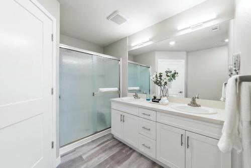 a white bathroom with a shower and a sink at Designer Apt with Jacuzzi, Pool & Mountain Views in Sparks