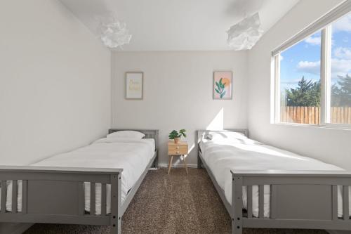 two beds in a white room with a window at DT Reno Elegant Home with Private Patio & BBQ Grill in Reno