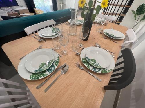 une table en bois avec des assiettes et de l'argenterie dans l'établissement T3 COSY MAISON DE VILLE TERRASSE AU CALME, à Rochefort