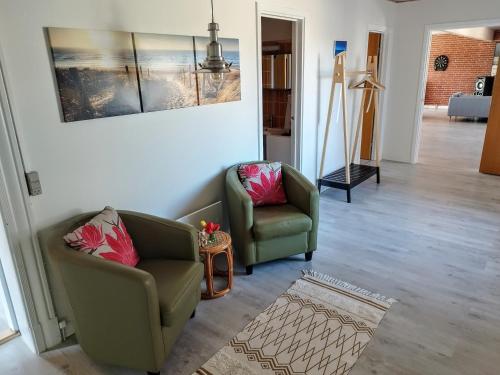 a living room with two chairs and a painting on the wall at Ferielejlighed Rubjerg Præstegård in Løkken