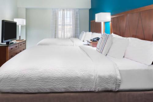 1 Schlafzimmer mit 2 weißen Betten und einem TV in der Unterkunft Residence Inn by Marriott St. Louis Downtown in Saint Louis