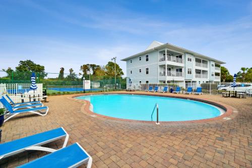 a swimming pool with blue chairs and a building at Beachside Villas by Panhandle Getaways in Seagrove Beach