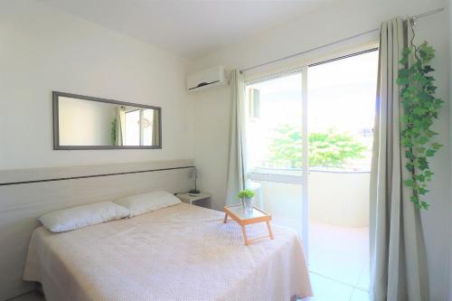 1 dormitorio con cama con espejo y ventana en Maravilhoso apto wi-fi e vista para o mar - HB06F, en Florianópolis