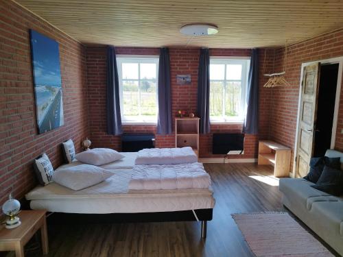 a bedroom with two beds and a brick wall at Ferielejlighed Rubjerg Præstegård in Løkken
