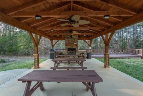 a picnic table under a wooden pavilion with a fireplace at Fully Stocked Cabin Retreat w/ Game Room & Pond! in Marion