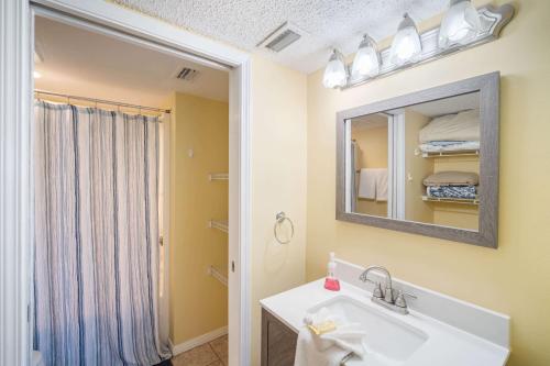 uma casa de banho com um lavatório, um espelho e um chuveiro em Plantation Palms 6110 by ALBVR - Upgraded Ground Floor Beachfront Condo - Lots of Amenities em Gulf Highlands
