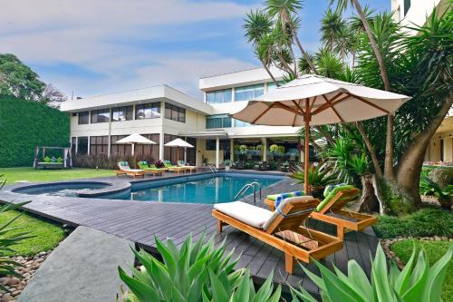a resort with a swimming pool with chairs and an umbrella at Auténtico Hotel in San José