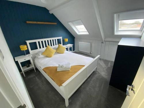 a bedroom with a white bed with yellow pillows at Tenby hideaway - by the beaches in Tenby