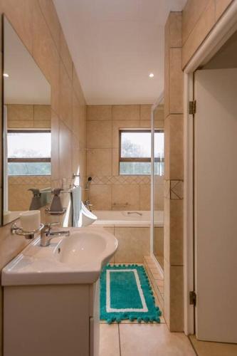 a bathroom with a sink and a bath tub at Copina Holiday Home in De Kelders