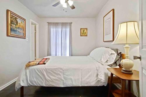 a white bedroom with a bed and a table with a lamp at Cozy & Family-friendly House In Heart Of Okc in Oklahoma City