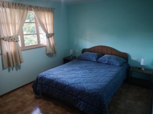 a bedroom with a bed with a blue comforter and a window at Cabaña Jacarandá in Salamanca