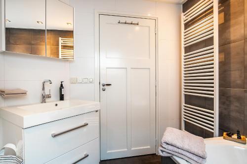 ein weißes Badezimmer mit einem Waschbecken und einem Spiegel in der Unterkunft Nummertje50 in Wommels