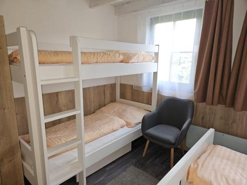 a bedroom with two bunk beds and a chair at chatka Tatralandia 433 Sofinka in Liptovský Mikuláš