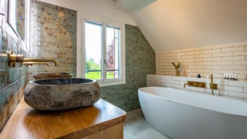 La salle de bains est pourvue d'une grande baignoire sur une table. dans l'établissement Maison Zugno Hôtel & Spa, à Barretaine