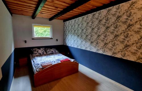 a small bedroom with a bed with a blue wall at Mazurski Kubryk in Ruciane-Nida