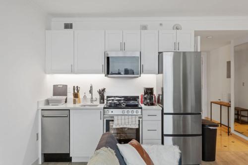 a kitchen with white cabinets and a stainless steel refrigerator at Beachfront 1BR 2BA Condo CozySuites at Showboat in Atlantic City