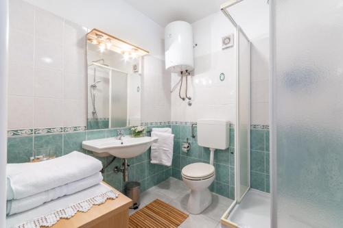uma casa de banho com um WC, um lavatório e um chuveiro em Apartments LOTA with heated pool on top location em Supetar