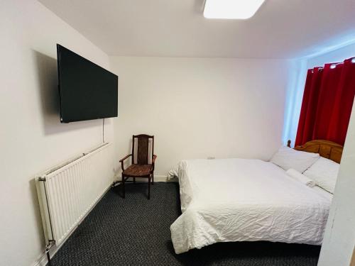UNIQUE PRIVATE ROOMS في بولتون: غرفة نوم مع سرير وتلفزيون على الحائط