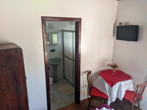 a room with a table and a bathroom with a sink at Pousada dos Marins in Campos do Jordão