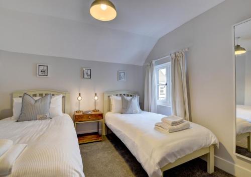 a bedroom with two beds and a window at Whimbrel Cottage in Appledore