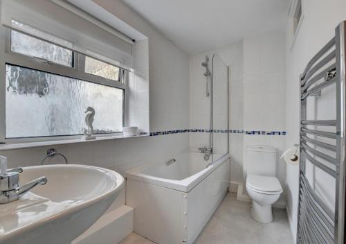 a bathroom with a tub and a toilet and a sink at Whimbrel Cottage in Appledore
