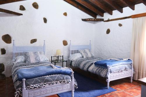 2 camas en una habitación con paredes blancas en Casa Rural Felipe Luis, en San Juan de la Rambla