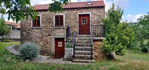 a stone house with a red door and stairs at Casa do Loureiro in Ferrarias
