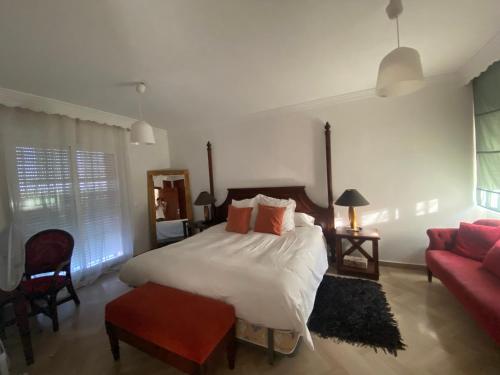 a bedroom with a large bed and a red couch at Casa Delfina in Estepona