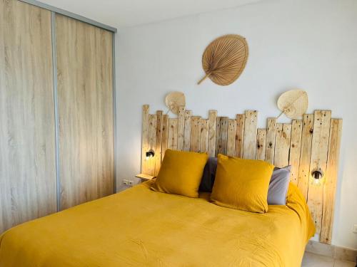 um quarto com uma cama amarela e uma cabeceira em madeira em Appartement VAIANA avec piscine en bord de mer em Ajaccio