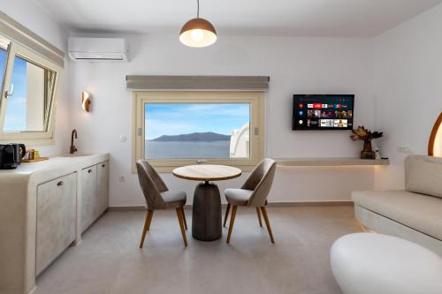 sala de estar con mesa, sillas y ventana en Santorini View Studios - Firostefani Caldera en Firostefani