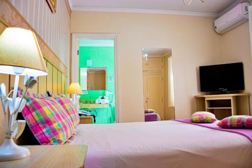 a bedroom with a bed with a lamp and a television at VELINN Pousada Chateau do Luar Prime in Campos do Jordão