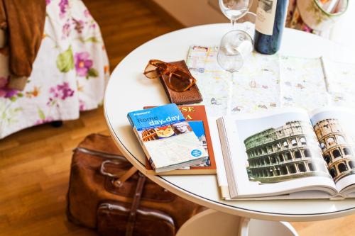 una mesa blanca con libros y una copa de vino en Villa Paganini B&B, en Roma