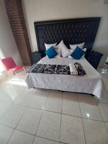 a bedroom with a large bed with blue pillows at 26 Zea avenue Arcon Park Guest House in Vereeniging