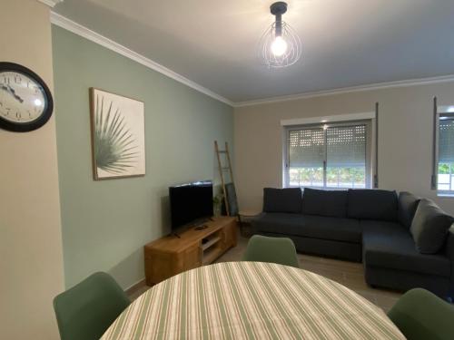 a living room with a couch and a table and a clock at Apartamento flor de amendoeira in Albufeira