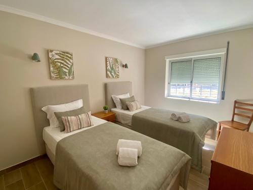 Cette chambre comprend 2 lits et une fenêtre. dans l'établissement Apartamento flor de amendoeira, à Albufeira