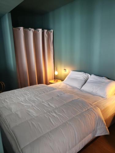 a large bed with white sheets and a lamp on a table at Le Paille en Queue in Fouesnant