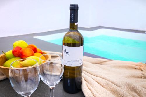 una botella de vino y dos copas junto a un bol de fruta en WHITE BREEZE VILLAS en Éxo Goniá