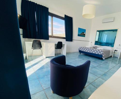 a living room with a bed and chairs in it at Capo Nettuno Hotel in Capo dʼOrlando