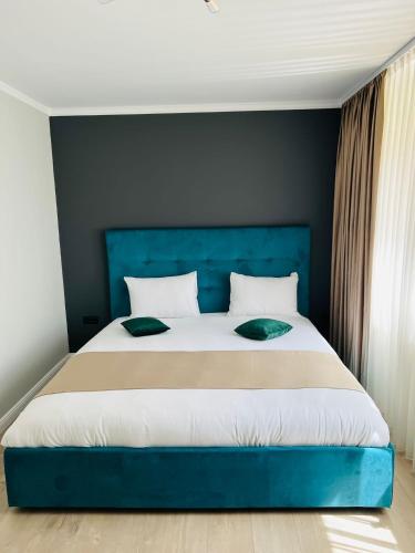 a large bed with a blue headboard in a bedroom at Apart Central in Orşova