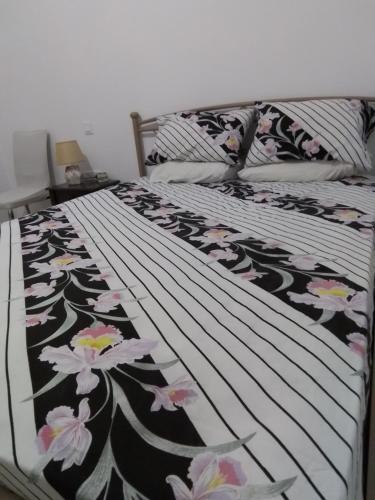 a bed with a black and white comforter with flowers on it at Kiki Apartment in Naxos Chora