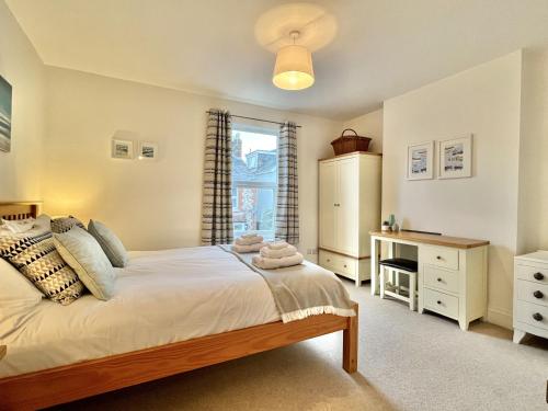 a bedroom with a bed and a desk and a window at Wickland Cottage in Chichester