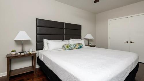 um quarto com uma grande cama branca e uma cabeceira preta em Bold CozySuites with pool, gym, roof #8 em Dallas