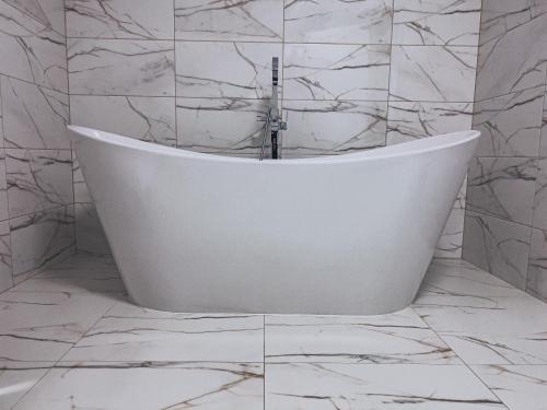 y baño con bañera blanca y azulejos de mármol. en Agroturystyka u Maryli, en Stronie Śląskie