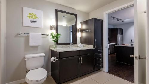 uma casa de banho com um WC e um lavatório com um espelho. em Bold CozySuites with pool, gym, roof #3 em Dallas