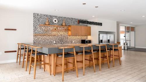 a kitchen with a bar with wooden stools at Bold CozySuites with gym, roof #3 in Dallas